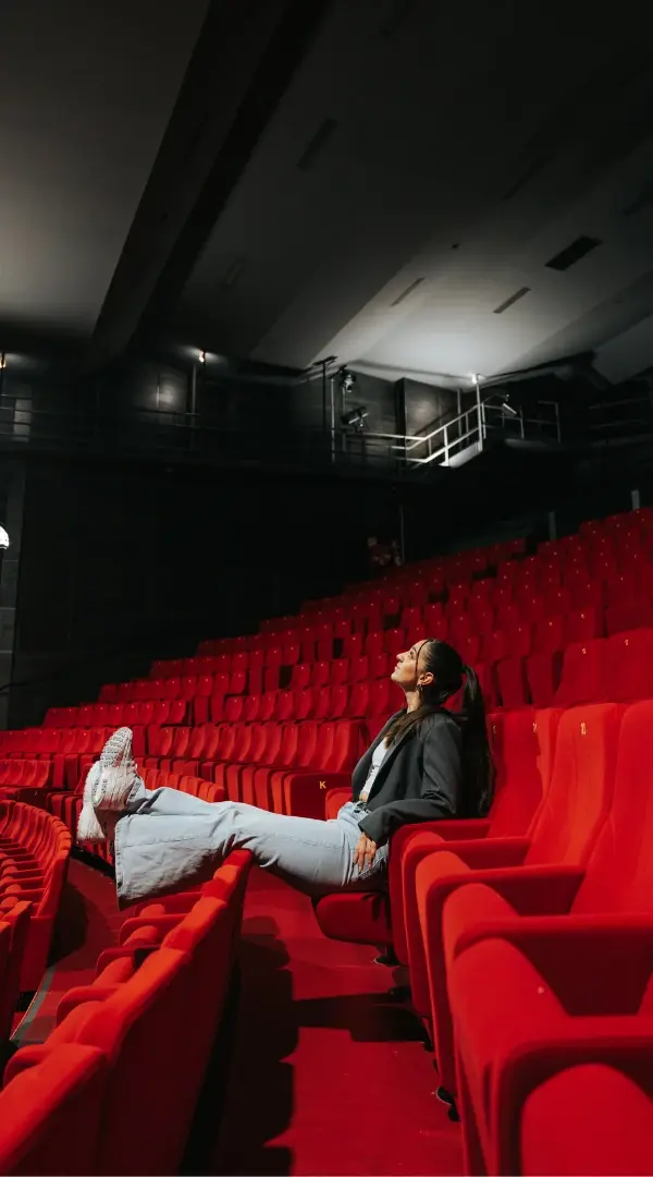 Julia Ortola allongée sur les fauteuils rouges de la salle vide